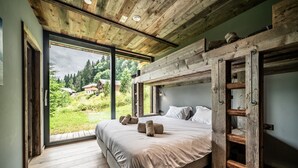 A bedroom with a large bed, wooden ceiling, and a view of a green landscape.