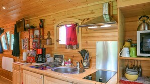 L’intérieur d’une cabane en bois comprend un espace cuisine équipé d’un évier, d’une cuisinière et de divers ustensiles de cuisine.