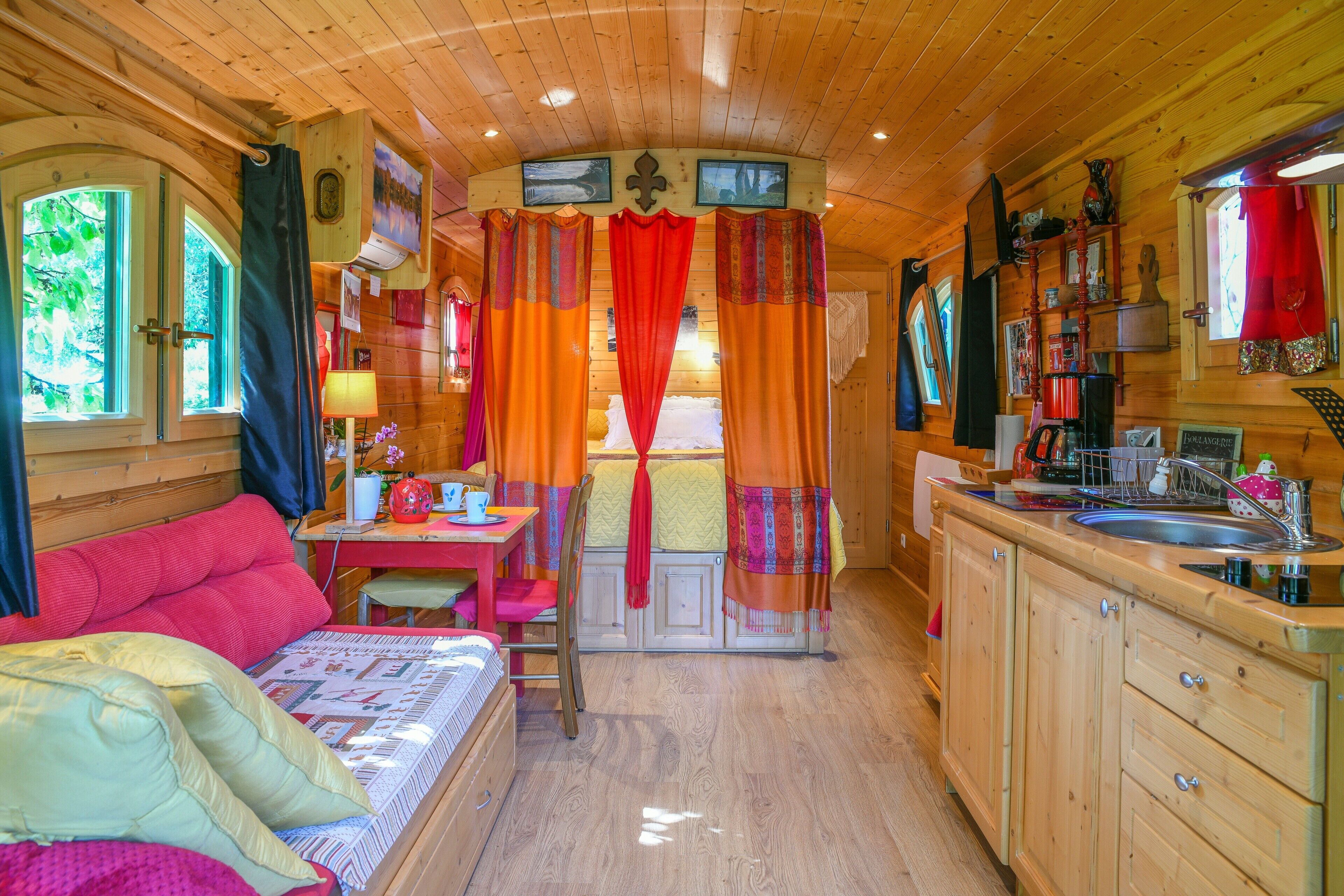 Ein gemütliches Blockhaus-Interieur mit Bett, Essbereich, Küche und einem Fenster mit Vorhängen.