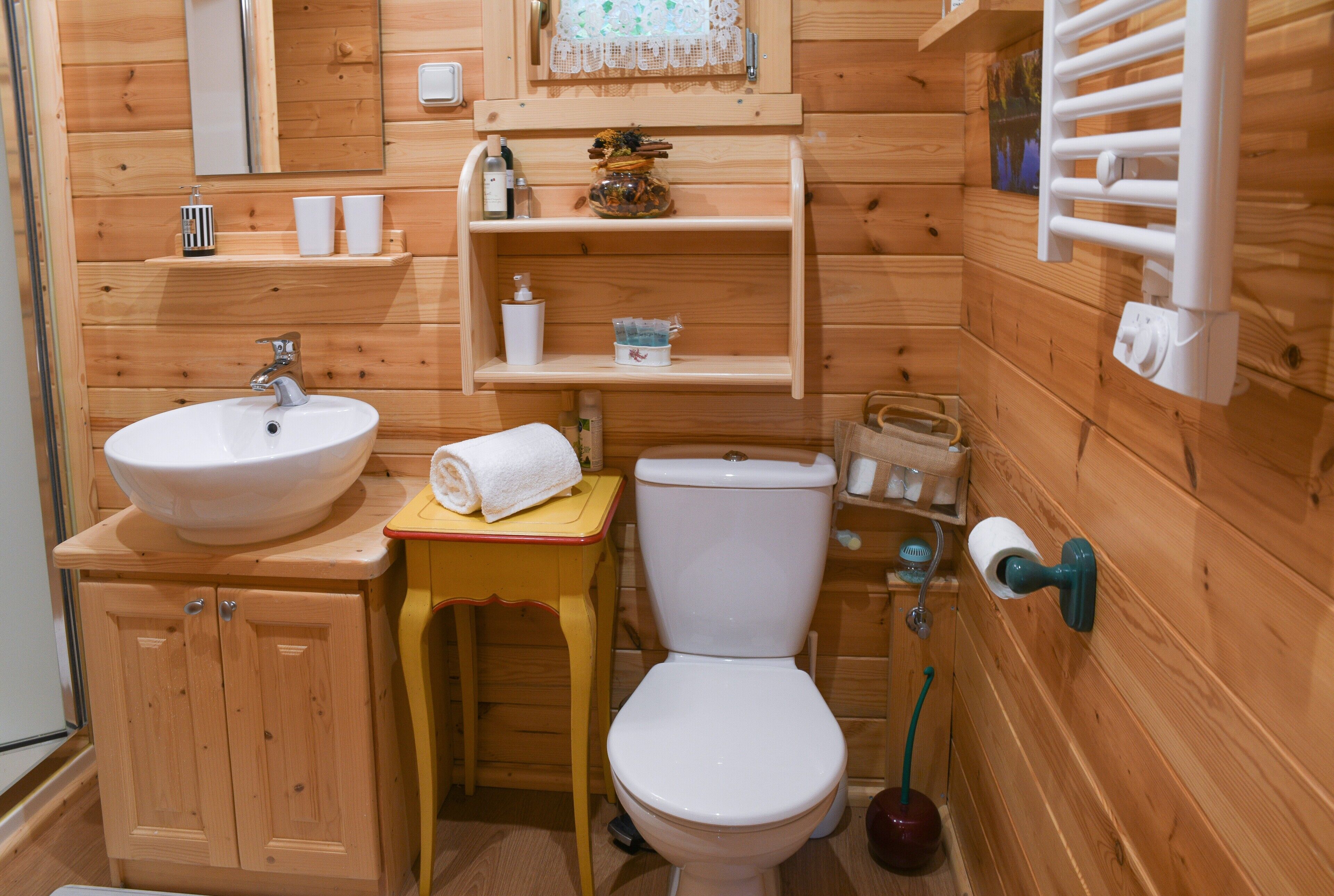 A wooden bathroom with a sink, toilet, and shelves.
