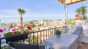 A balcony with a table, chairs, and potted plants.