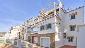 A multi-story residential building with balconies, a garage, and a stone facade.