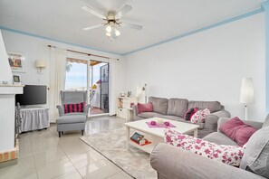 A living room with a sofa, armchair, coffee table, and a television.