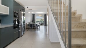 A modern kitchen with a dining area, a staircase, and a view to the outside. - Holiday Home 'Bonita' with Sea Views, Shared Pool and Wi-Fi (ZAHARA DE LOS ATUNES)