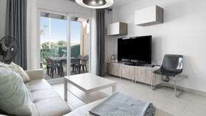 A modern living room with a sofa, a coffee table, a TV, and a dining area with chairs and a table. - Holiday Home 'Bonita' with Sea Views, Shared Pool and Wi-Fi (ZAHARA DE LOS ATUNES)