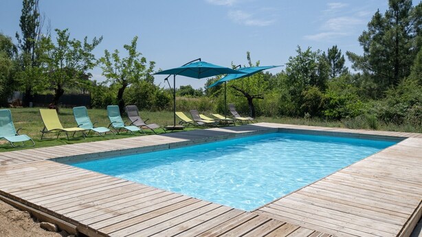 A rectangular swimming pool with a wooden deck, surrounded by green lawn and trees. - Villa 'Hamlet' with Private Pool, Private Terrace and Wi-Fi (LABLACHÈRE)
