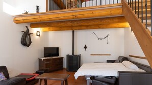 A cozy room with a bed, a TV, a wooden bench, and a staircase. - Villa 'Hamlet' with Private Pool, Private Terrace and Wi-Fi (LABLACHÈRE)