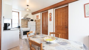 Een keuken met witte kasten, een fornuis en een eettafel met stoelen.