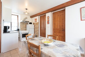 A kitchen with white cabinets, a stove, and a dining table with chairs.