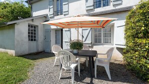 Een terras met een tafel, stoelen en een gestreepte parasol.