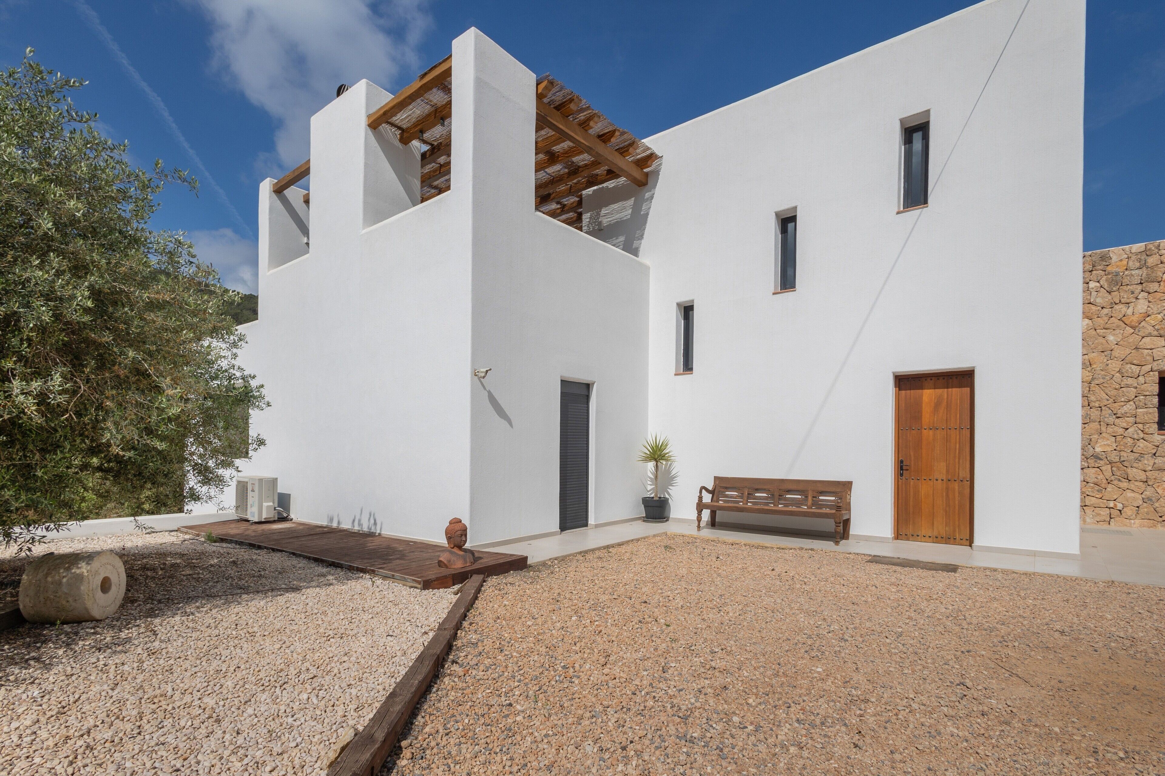 Un edificio moderno con fachada blanca, puerta de madera y pared de piedra.