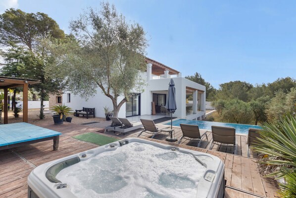 Un espace piscine extérieur moderne, doté de chaises longues, d’un jacuzzi et d’une terrasse en bois.