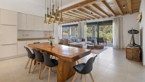 Eine geräumige Küche mit einer Holztheke, modernen Stühlen und Pendelleuchten.