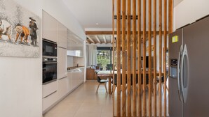 Eine moderne Küche mit integriertem Backofen, einem Kühlschrank und einem Essbereich mit Holztisch und Stühlen.