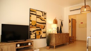 Un salon équipé d’un téléviseur à écran plat, d’un meuble en bois, d’œuvres d’art, d’une lampe et d’une plante en pot.