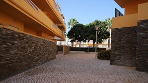 Une cour dallée de pierres, un mur en pierre et un bâtiment doté de balcons.