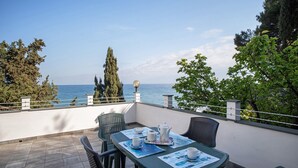 Une terrasse avec une table dressée pour le thé, des chaises et une vue sur la mer.