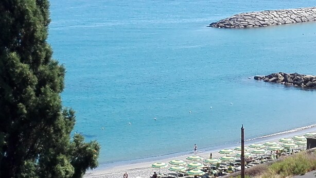 Une plage avec des parasols et une digue rocheuse.