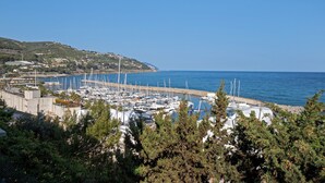 Un port de plaisance où sont amarrés des bateaux, entouré de verdure et de collines.