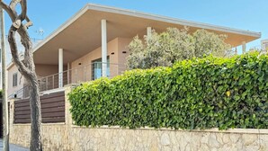 Un edificio moderno con un muro de piedra y un seto verde al frente.