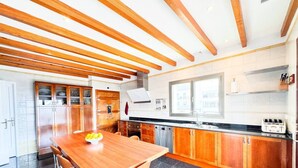 Una cocina moderna con vigas de madera, una mesa de comedor con sillas y un ventanal que proporciona luz natural.