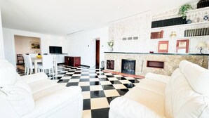 Una sala de estar con suelo a cuadros, sofás blancos, una chimenea y una estantería.