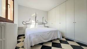 A bedroom with a bed, a radiator, a wardrobe, and a checkered floor. - Holiday Home 'Cala Estancia' with Private Terrace, Wi-Fi and Air Conditioning (Can Pastilla)
