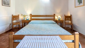 Een slaapkamer met een houten bed, twee nachtkastjes met lampen, een nachtkastje en een stoel.
