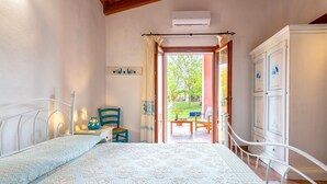 A bedroom with a bed, a chair, a small table, and a wardrobe.