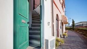 Un edificio con una puerta verde, una escalera que lleva a la entrada y un letrero del restaurante 'POZZI' a la derecha.