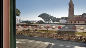 Vista de una calle con un muro de piedra, una carretera con líneas blancas y un edificio con una torre.