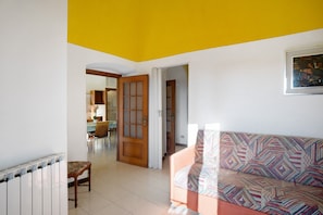 A living room with a patterned sofa, a wooden door, and a radiator.