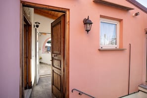 A hallway with a wooden door, a window with a view, and a wall-mounted light fixture.