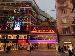 Un bâtiment avec une enseigne au néon portant l’inscription « ARISTON » et l’entrée d’un cinéma.