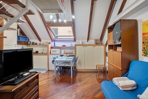 A compact living space with a dining area, kitchenette, and a blue sofa.