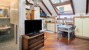 A compact kitchen with a TV, wooden cabinets, and a dining area with chairs. - Apartment 'Lovely Loft' with Wi-Fi and Air Conditioning (Sanremo)