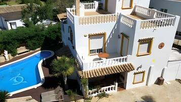 Un edificio de varios pisos con piscina, balcones y un jardín.