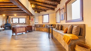 Un intérieur rustique avec des poutres apparentes, une cheminée en pierre, un banc en bois et un mur de pierres.