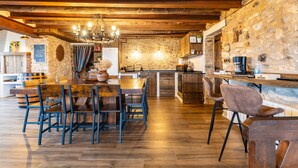 Une cuisine rustique avec des poutres en bois, des murs en pierre et un îlot central doté de tabourets de bar.