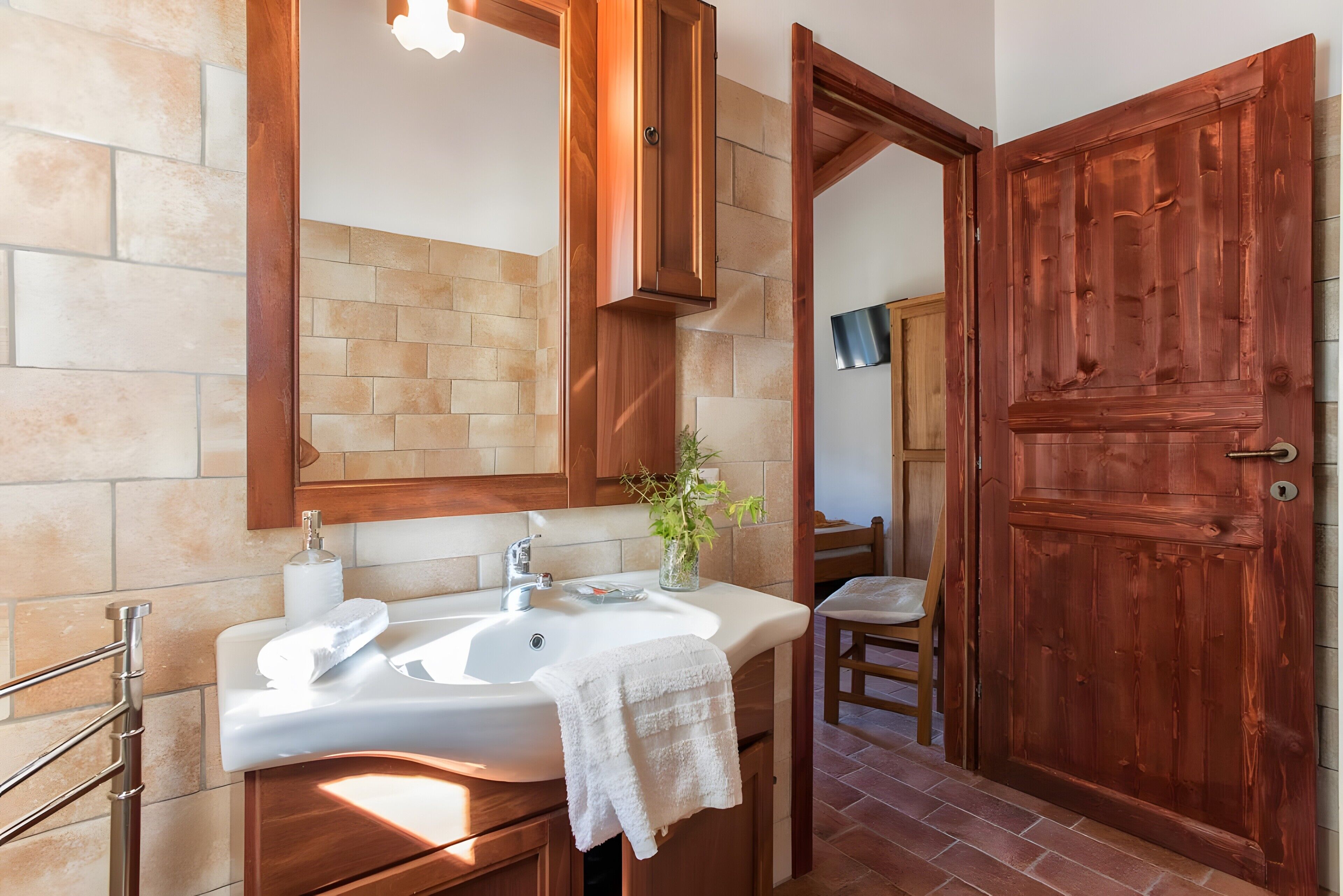 Une salle de bain avec un lavabo, un miroir et une porte en bois.