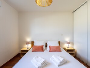 A hotel room with a large bed, two bedside tables, a wooden headboard, and a ceiling light fixture.