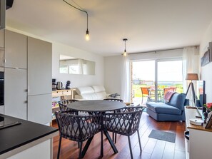 Eine moderne Küche mit Essbereich, einer Couch und einem Balkon mit Gartenmöbeln.