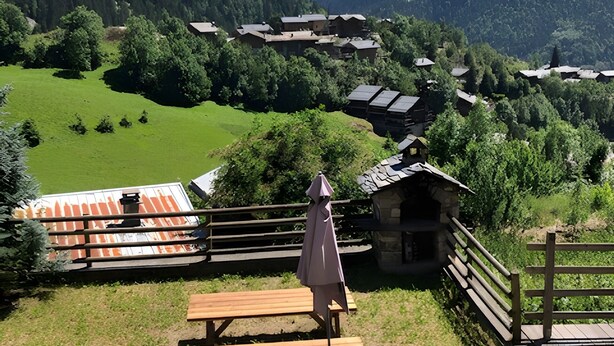 A mountain view with a wooden deck, chairs, and a table.