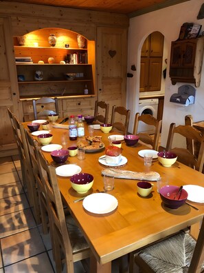 A wooden dining table set with plates, bowls, and glasses, surrounded by chairs.