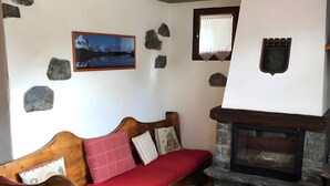 A cozy room with a wooden sofa, a stone fireplace, and a framed picture on the wall.