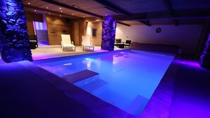 A swimming pool with stone pillars, lounge chairs, and a wooden ceiling. - Apartment 'Roméo' with Mountain View, Private Terrace and Shared Garden (Champagny-en-Vanoise)