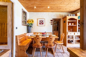Un comedor de madera con una mesa dispuesta para cuatro, sillas de madera y un banco.