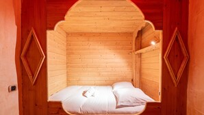 A wooden cabin with a single bed, a small window, and a unique arched ceiling. - Apartment 'Roméo' with Mountain View, Private Terrace and Shared Garden (Champagny-en-Vanoise)