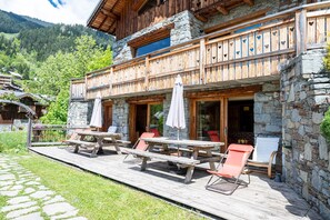 Un chalet en bois doté d’un balcon, de murs en pierre et d’un espace salon extérieur.