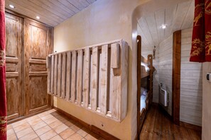 Un couloir aux murs en bois, avec un radiateur et un lit.